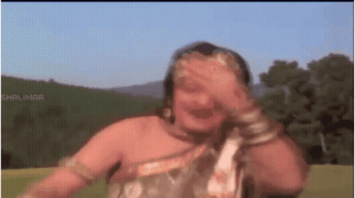 A Woman Is Covering Her Face With Her Hand While Dancing In A Field . GIF