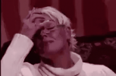 A Woman Is Covering Her Face With Her Hand While Sitting On A Couch . GIF
