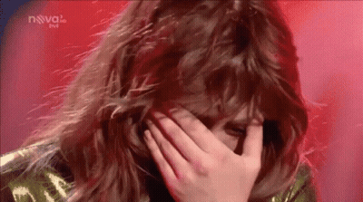 a woman is covering her face with her hand while standing on a stage .