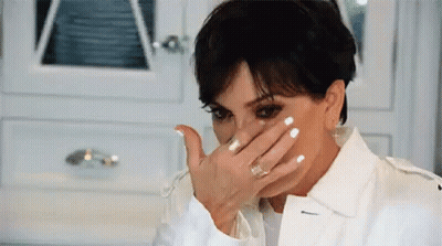 A Woman Is Covering Her Face With Her Hand While Wearing A White Jacket . GIF