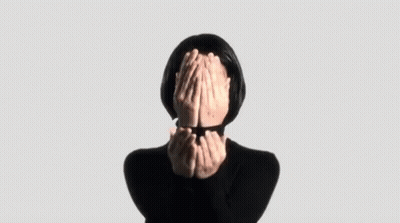 A Woman Is Covering Her Face With Her Hands In A Black Sweater . GIF
