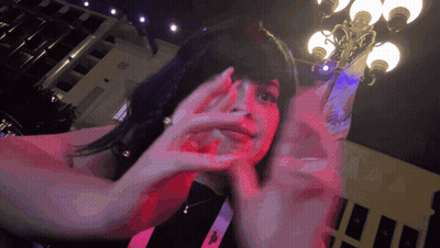 A Woman Is Covering Her Face With Her Hands In Front Of A Building GIF
