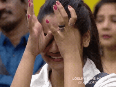 A Woman Is Covering Her Face With Her Hands While Sitting In A Crowd . GIF