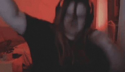 A Woman Is Covering Her Face With Her Hands While Sitting In Front Of A Computer Screen . GIF