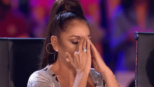 A Woman Is Covering Her Face With Her Hands While Wearing A Ring . GIF