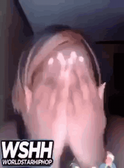 A Woman Is Covering Her Face With Her Hands While Wearing Headphones And A Headband . GIF