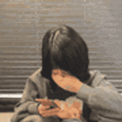 A Woman Is Covering Her Mouth While Looking At Her Phone . GIF