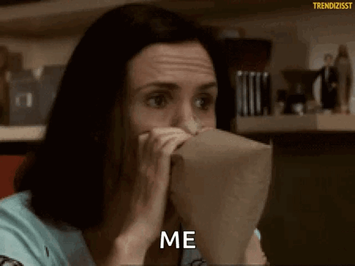 A Woman Is Covering Her Mouth With A Paper Bag And Saying Me . GIF