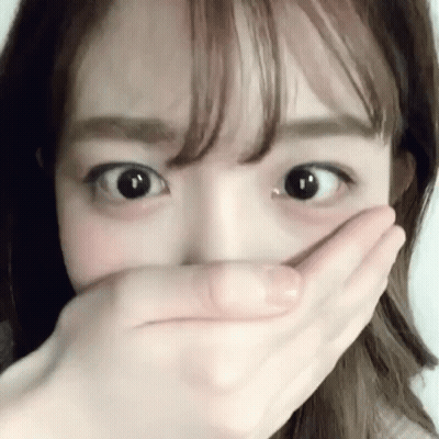A Woman Is Covering Her Mouth With Her Hand And Looking At The Camera . GIF