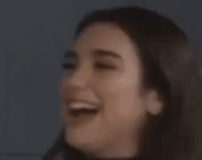 A Woman Is Covering Her Mouth With Her Hand And Looking At The Camera . GIF