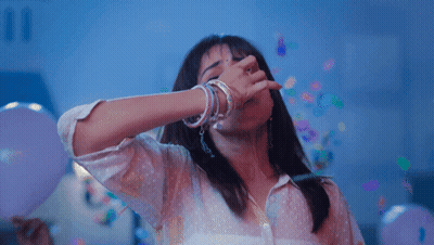A Woman Is Covering Her Mouth With Her Hand While Confetti Falls Around Her GIF