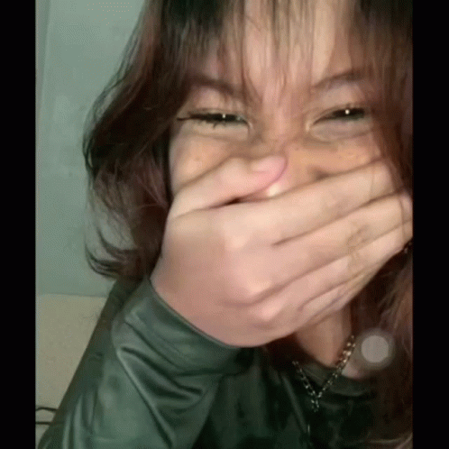 A Woman Is Covering Her Mouth With Her Hand While Laughing . GIF