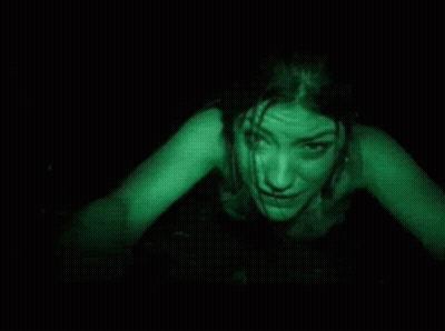 A Woman Is Crawling In The Dark With Green Light Coming Out Of Her Eyes . GIF