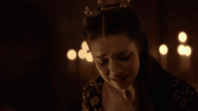 A Woman Is Crying In A Dark Room With Candles Behind Her GIF