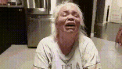 A Woman Is Crying In A Kitchen With Her Eyes Closed And Her Mouth Open . GIF