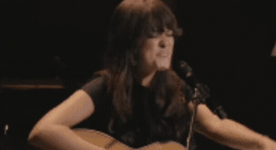 A Woman Is Crying In Front Of A Lamp In A Dark Room GIF