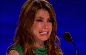A Woman Is Crying In Front Of A Microphone While Wearing A Green Dress . GIF