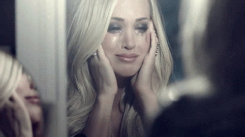 A Woman Is Crying In Front Of A Mirror While Looking At Herself . GIF