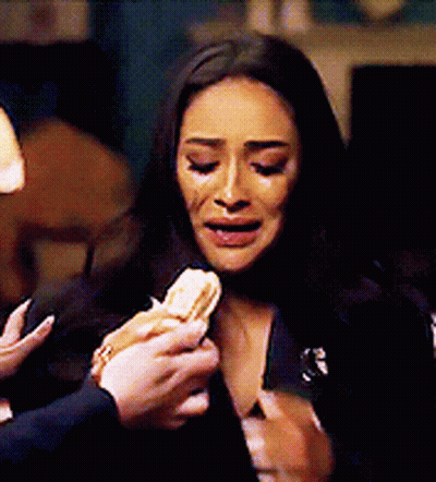 A Woman Is Crying While A Man Is Holding A Sandwich In Front Of Her . GIF