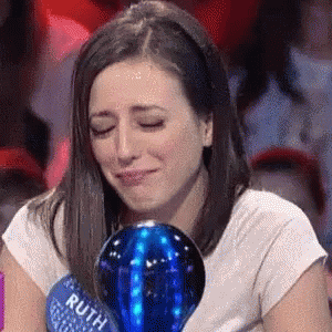 A Woman Is Crying While Holding A Blue Ball That Says Ruth On It GIF