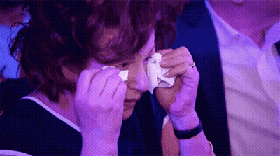 A Woman Is Crying While Holding A Tissue To Her Eye . GIF