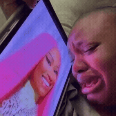 A Woman Is Crying While Looking At A Picture Of Nicki Minaj On A Computer Screen . GIF