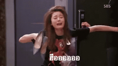 A Woman Is Crying While Sitting On A Chair In Front Of A Door . GIF