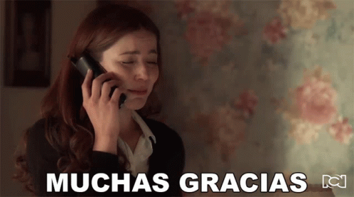 A Woman Is Crying While Talking On A Cell Phone With The Words Muchas Gracias Written Below Her GIF