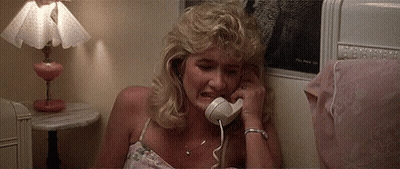 A Woman Is Crying While Talking On A Phone In A Bedroom . GIF