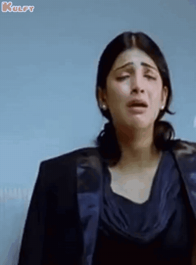 A Woman Is Crying While Wearing A Black Jacket And A Blue Top . GIF