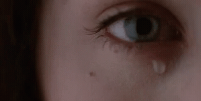 A Woman Is Crying With A Tear Coming Out Of Her Eye . GIF