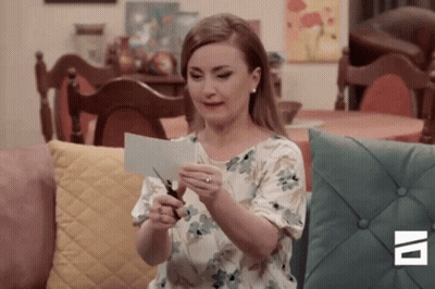 A Woman Is Cutting A Piece Of Paper With Scissors . GIF