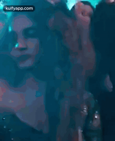 A Woman Is Dancing In A Club With Her Hands In The Air And Smiling . GIF