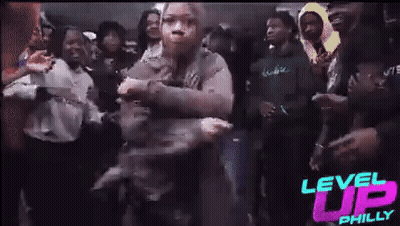 A Woman Is Dancing In A Crowd Of People At A Party . GIF