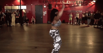 A Woman Is Dancing In A Dance Studio In Front Of A Crowd . GIF