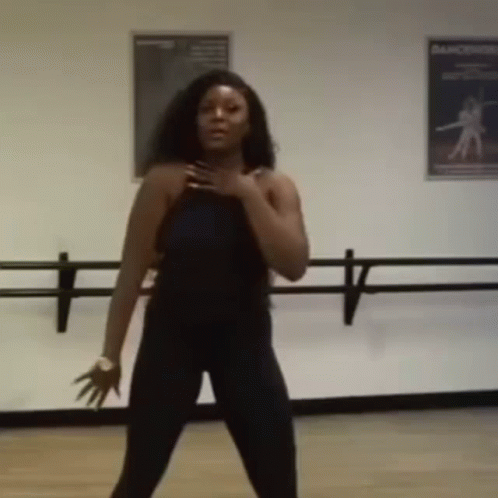 A Woman Is Dancing In A Dance Studio With A Dance Poster On The Wall GIF