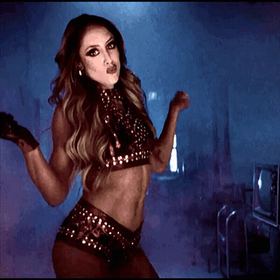 A Woman Is Dancing In A Dark Room Wearing A Crop Top And Shorts GIF