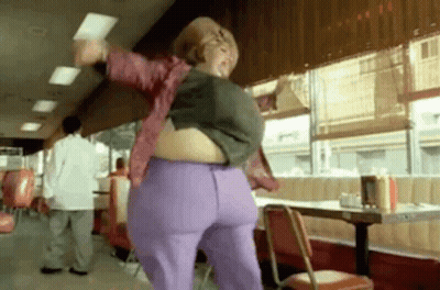 A Woman Is Dancing In A Diner With A Very Large Belly . GIF