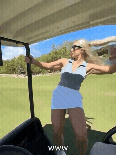 A Woman Is Dancing In A Golf Cart On A Golf Course While Wearing Sunglasses . GIF