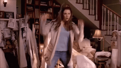 A Woman Is Dancing In A Living Room In Front Of Stairs . GIF