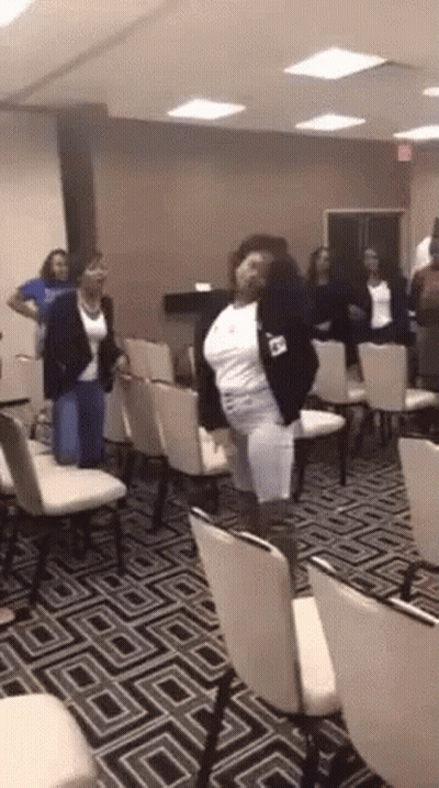 A Woman Is Dancing In A Room Full Of Chairs GIF