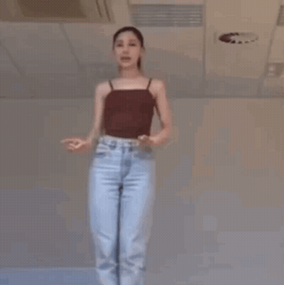A Woman Is Dancing In A Room With A Ceiling Fan . GIF