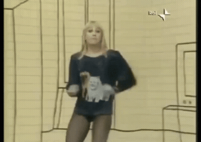 A Woman Is Dancing In A Room With A Drawing On The Wall Behind Her . GIF