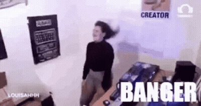 A Woman Is Dancing In A Room With The Words Banger Written On The Wall Behind Her . GIF