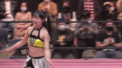 A Woman Is Dancing In A Wrestling Ring In Front Of A Crowd Of People . GIF