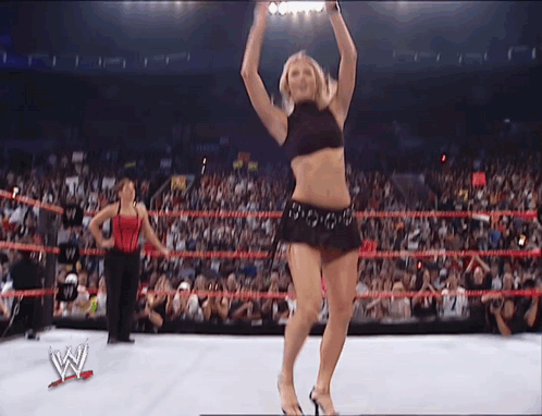 A Woman Is Dancing In A Wrestling Ring With The Letter W On The Bottom Right GIF