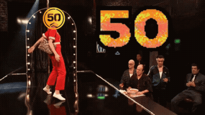 A Woman Is Dancing In Front Of A 50 Sign GIF