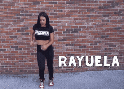 A Woman Is Dancing In Front Of A Brick Wall And The Name Rayuela Is On The Ground GIF