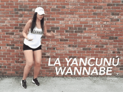 A Woman Is Dancing In Front Of A Brick Wall That Says La Yancunun Wannabe GIF