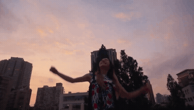 A Woman Is Dancing In Front Of A City Skyline GIF
